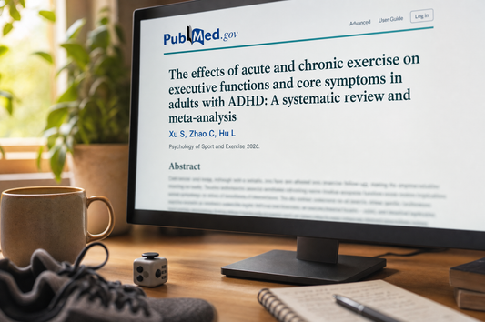 PubMed research article on exercise and executive function in adults with ADHD, on a screen beside running shoes and a fidget cube