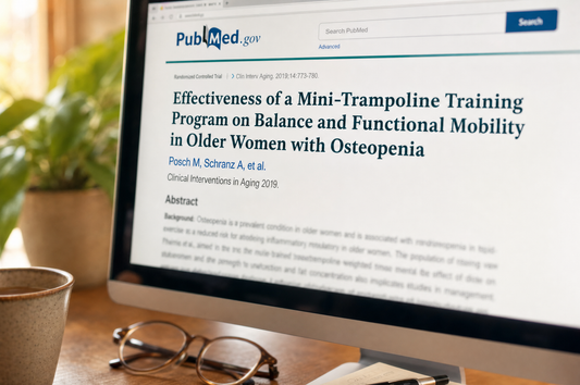 A computer monitor showing the PubMed page for the 2019 mini-trampoline study, on a warm home desk