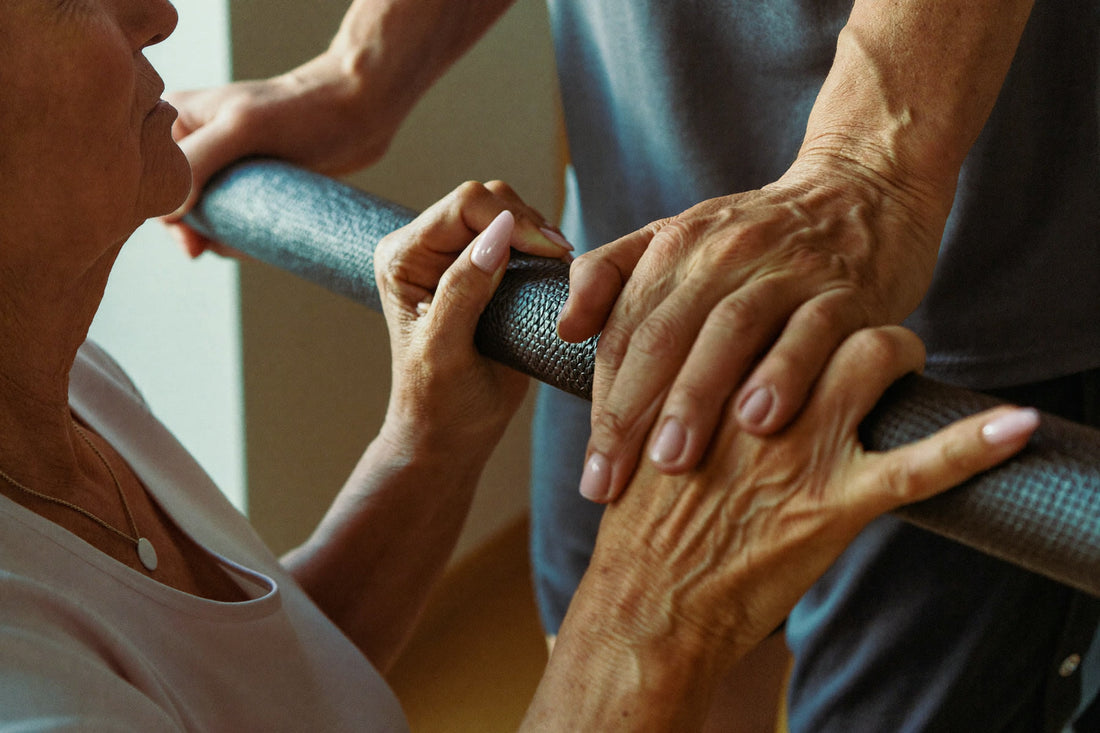 A coach's hand resting over an older woman's hand on a padded gym rail
